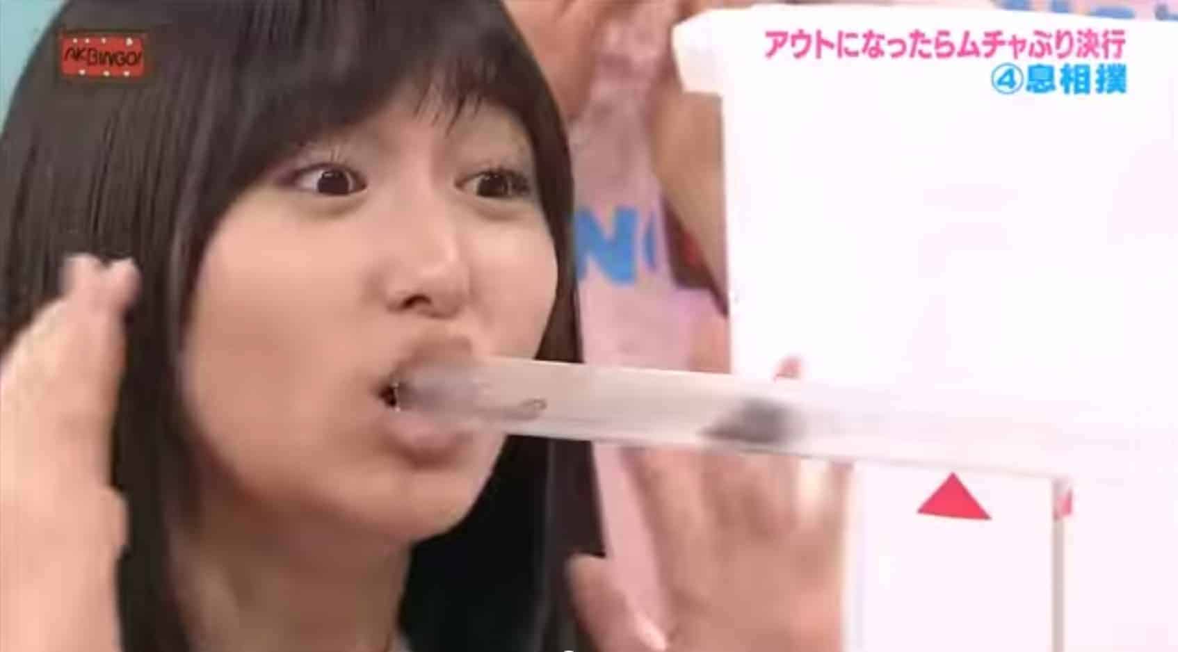 A woman is holding a plastic tube in her mouth while watching a cockroach.