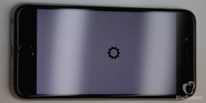 A black iPhone with a gear icon on the screen in a leaked video.
