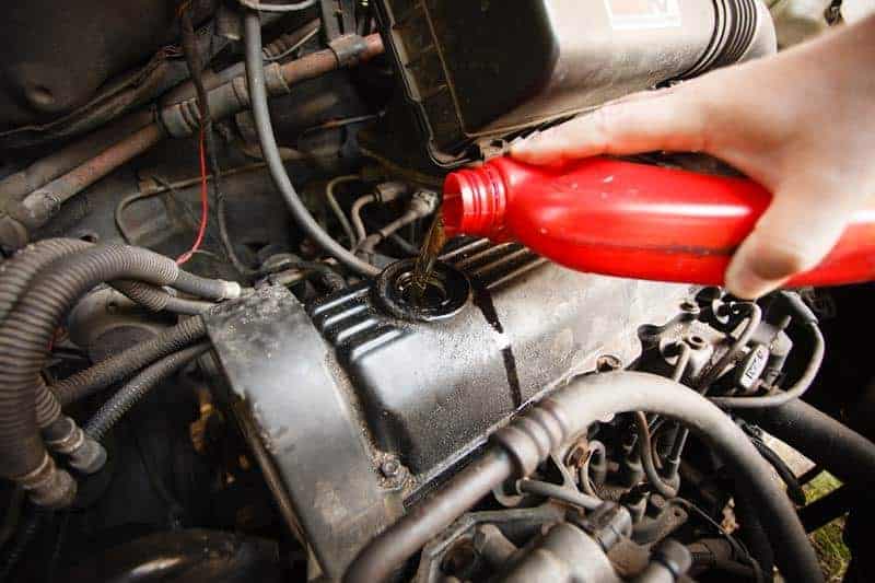 Car servicing mechanic pouring oil to engine. Closeup of fresh oil being poured into a car.