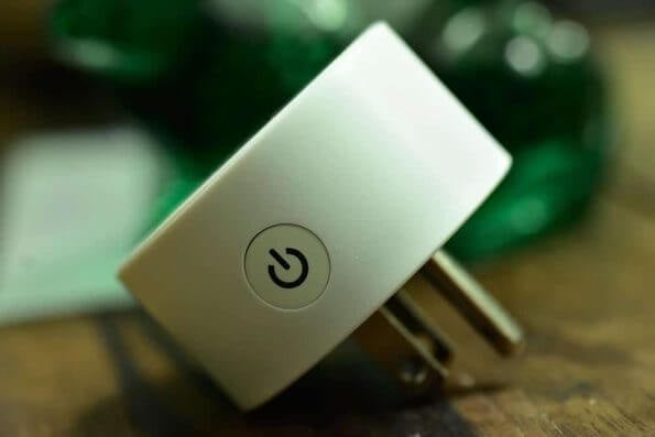 A white plug connected to a smart home automation system on a wooden table.