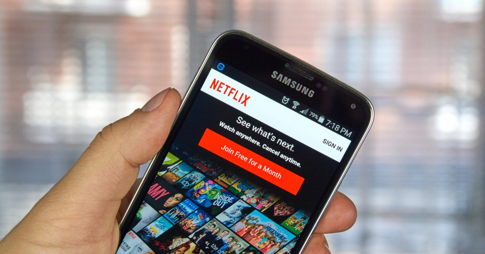 A person holds a Samsung phone displaying the Netflix app with various show thumbnails including Pinoy Movies Online offering a free trial