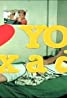 A person lies on a bed with vivamax-green sheets, surrounded by yellow text overlay that partially reads "YO." A small photo in the background shows two people interacting, possibly in a playful manner. The overall image captures a casual and candid atmosphere.