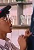 A person wearing a cap and glasses looks upwards, contemplating must-watch Filipino films, with shelves and glassware in the background.