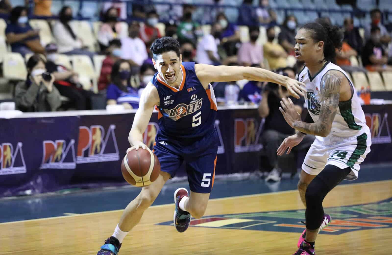 Meralco basketball player dribbles the ball on the court.
