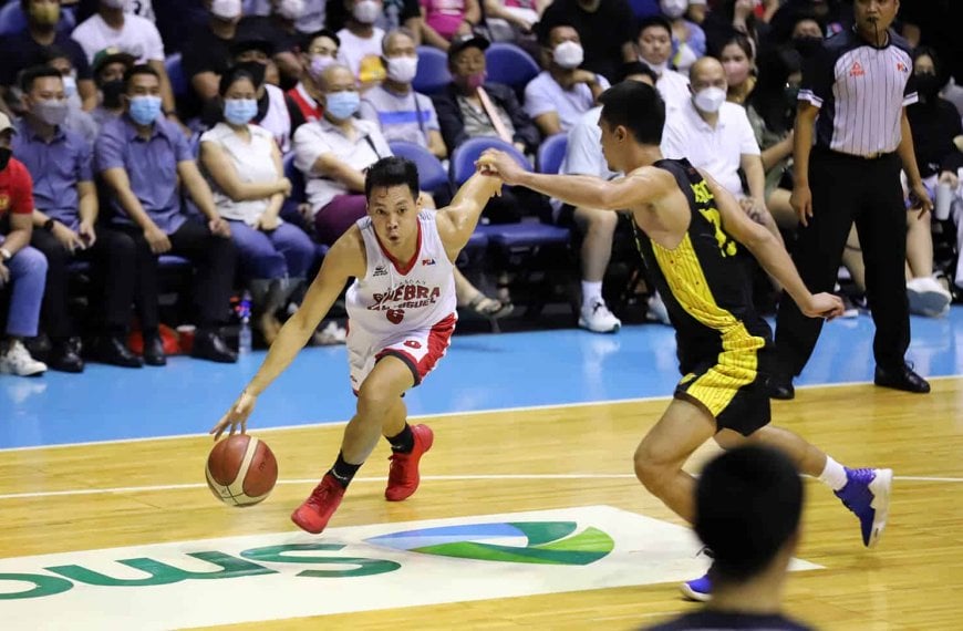 A basketball player dribbling the ball in front of a crowd during a PBA game.