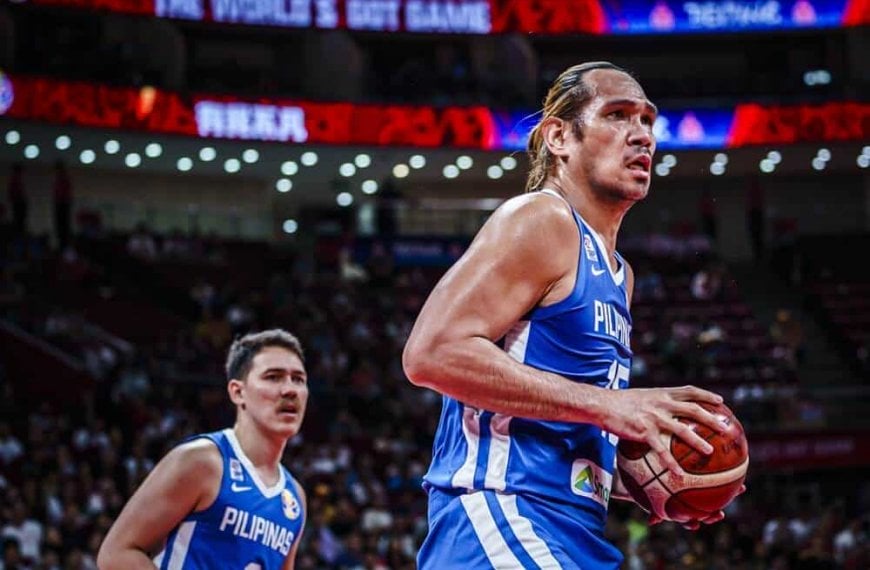 A basketball player, June Mar Fajardo, is holding a ball in front of a crowd during SEA Games.