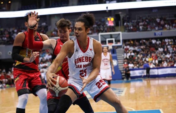 A basketball player named Japeth Aguilar from Ginebra is dribbling the ball in a game.