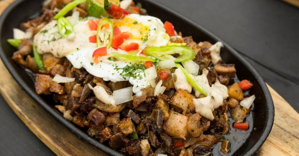 a plate of sisig with an egg on top from one of the 48 best restaurants in manila.