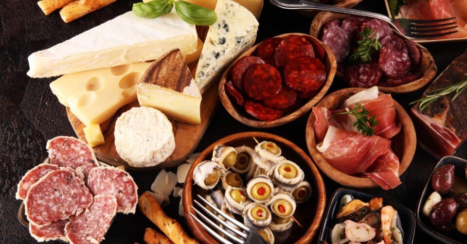 the ultimate charcuterie board, expertly crafting an assortment of meats, cheeses and breads on a wooden table.