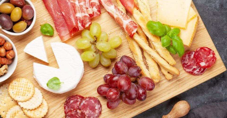 the ultimate charcuterie board, crafted from rich, polished wood and adorned with a delectable assortment of cheeses, crackers, and grapes.