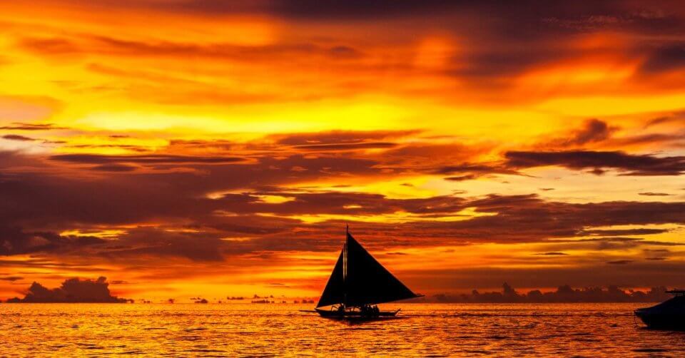 a sailboat gracefully sails in the ocean at sunset, creating a mesmerizing summer scene reminiscent of the breathtaking beauty found in the philippines one of the 30 must visit destinations for any