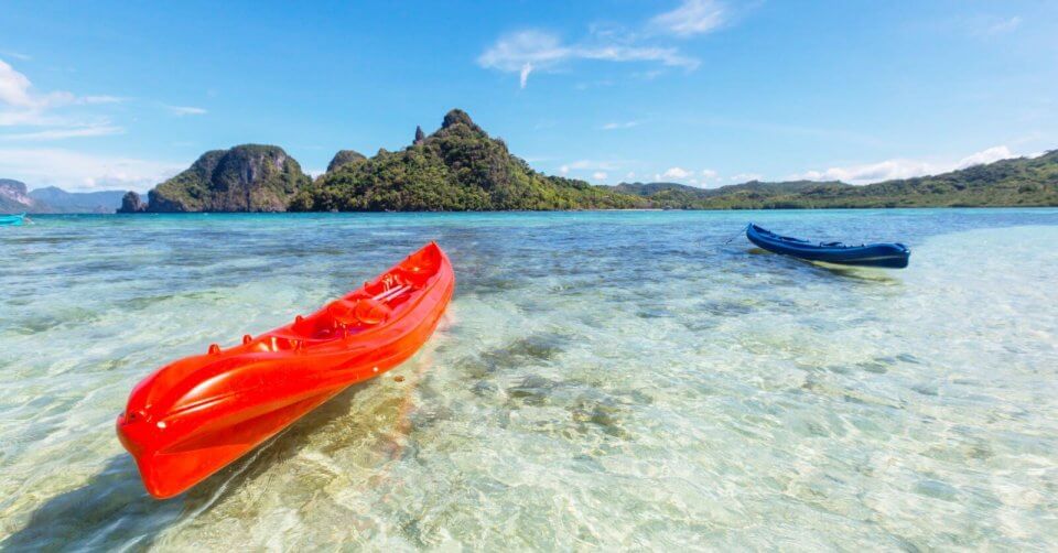 two red canoes in clear water near a mountain, creating a must visit destination in the philippines.