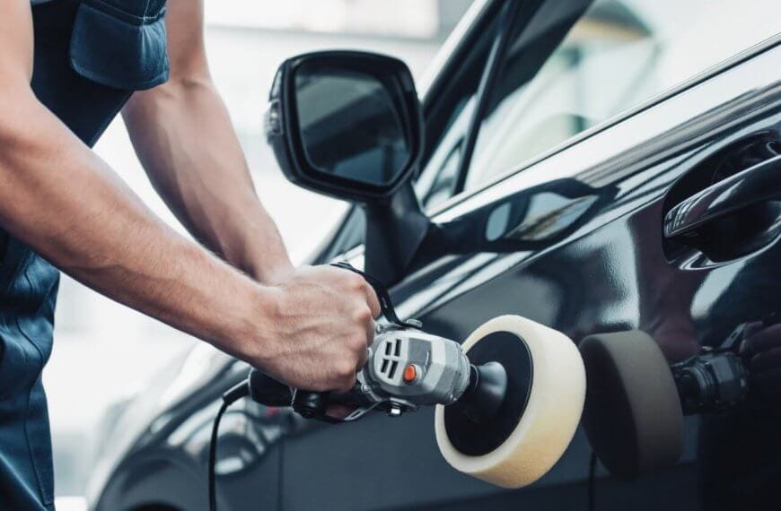 A man is polishing the door of a black car in Metro Manila.