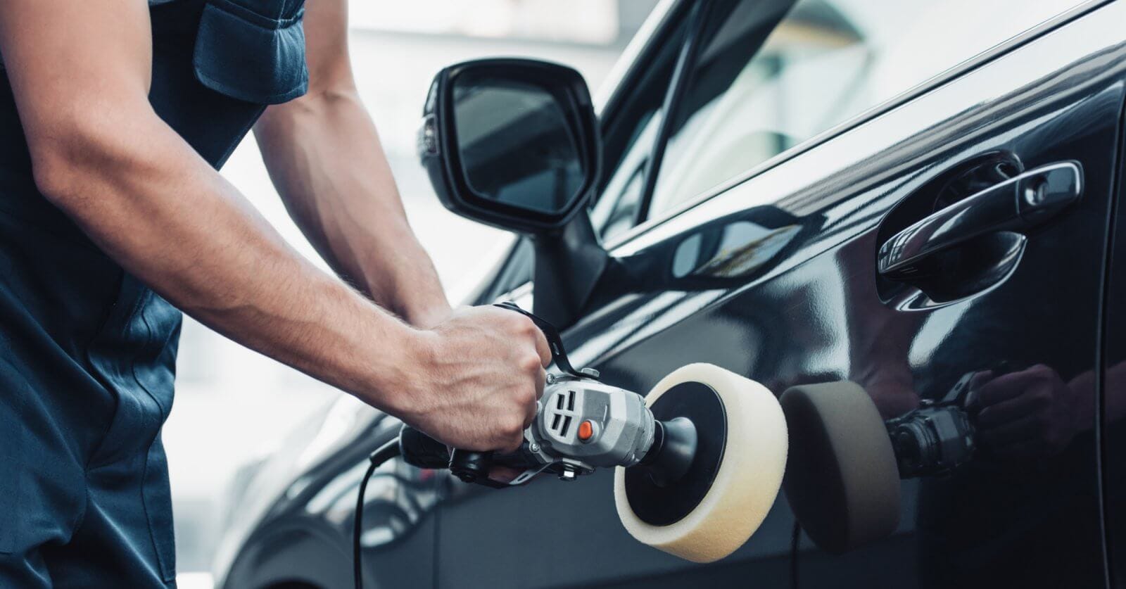 A man is polishing the door of a black car in Metro Manila.