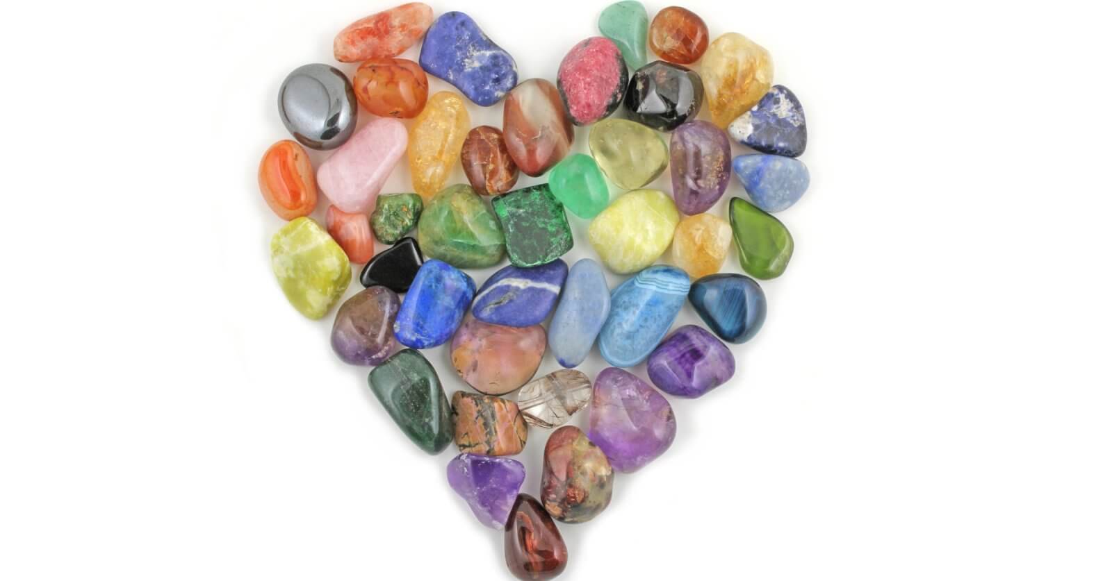 A heart shaped arrangement of colored crystals on a white background.