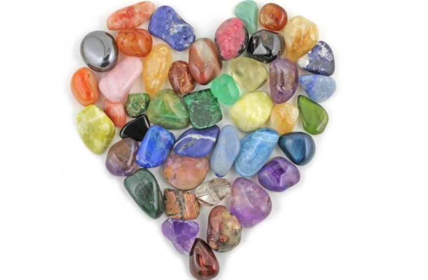 A heart shaped arrangement of colored crystals on a white background.