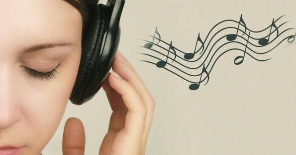 Close-up of a person with closed eyes wearing black headphones, holding the left earcup with their left hand. To the right, musical notes on a staff float against a light beige background, suggesting they are enjoying the Best OPM Songs. Only the left side of the person's face is visible.