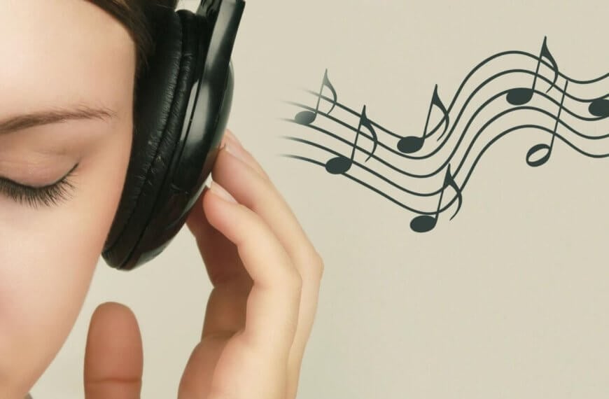 Close-up of a person with closed eyes wearing black headphones, holding the left earcup with their left hand. To the right, musical notes on a staff float against a light beige background, suggesting they are enjoying the Best OPM Songs. Only the left side of the person's face is visible.