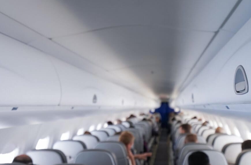 The interior of an airplane cabin with rows of occupied seats on a Cebu Pacific flight. The image shows overhead compartments closed and passengers are seated, facing forward towards the front of the plane. The lighting is bright, creating a clean and modern look. The distant cockpit area is visible but not detailed.