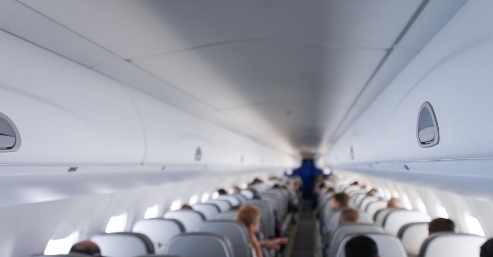 The interior of an airplane cabin with rows of occupied seats on a Cebu Pacific flight. The image shows overhead compartments closed and passengers are seated, facing forward towards the front of the plane. The lighting is bright, creating a clean and modern look. The distant cockpit area is visible but not detailed.