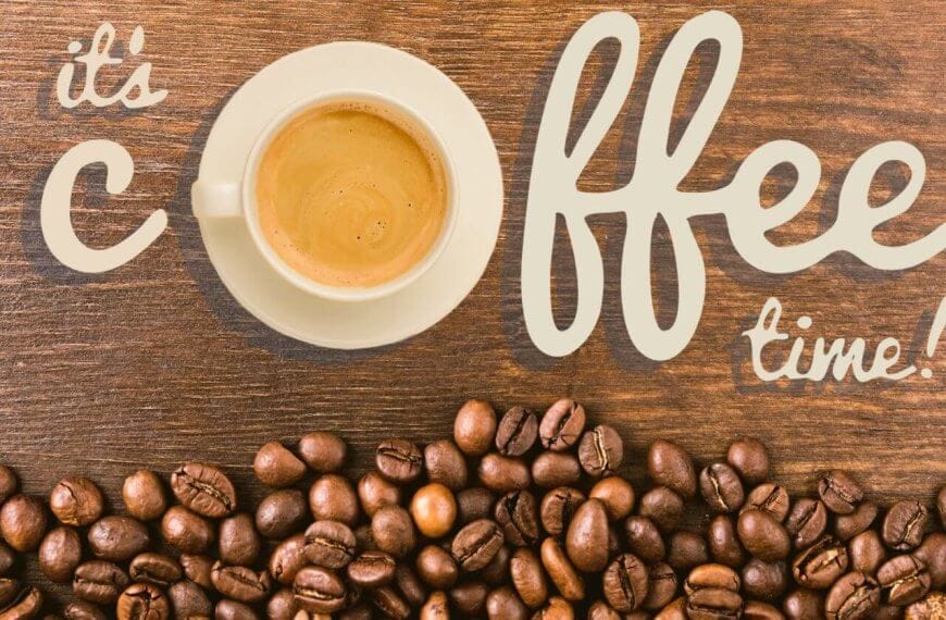 A white cup of coffee sits on a wooden surface, surrounded by scattered coffee beans. The words "it's coffee time!" are artistically written in beige lettering around the cup. The composition creates a cozy and inviting atmosphere that celebrates Antipolo's best coffee shops.