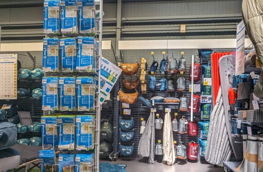 A well-organized camping gear section in one of the best camping stores in Metro Manila displays an array of neatly arranged outdoor equipment. On the left, air mattresses and travel pillows are stacked on shelves. The center showcases various hydration packs and bags. The right features sleeping bags and camping mats hanging on hooks.