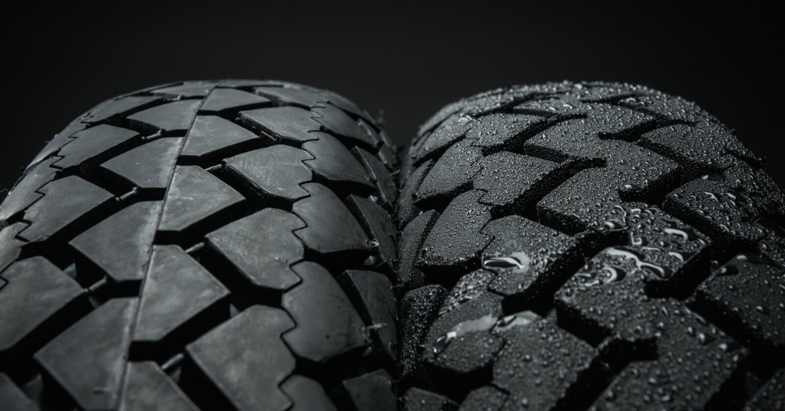 Close-up view of two motorcycle tires side by side against a black background. The tire on the left features a smooth tread, while the tire on the right has a rough tread pattern and is covered in water droplets, suggesting wet conditions. Both treads have interlocking block designs from top suppliers in Metro Manila.