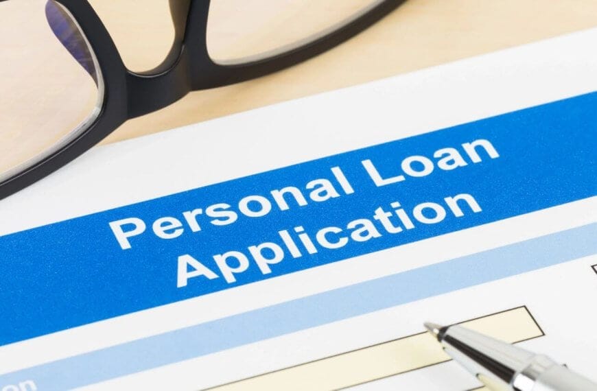 A close-up of a Sulit personal loan application form with a blue header. "Personal Loan Application" is prominently displayed. There's a pen on the form, and a pair of glasses is partially visible in the upper left corner. The form includes fields to fill in personal details alongside the convenient use of a loan calculator.