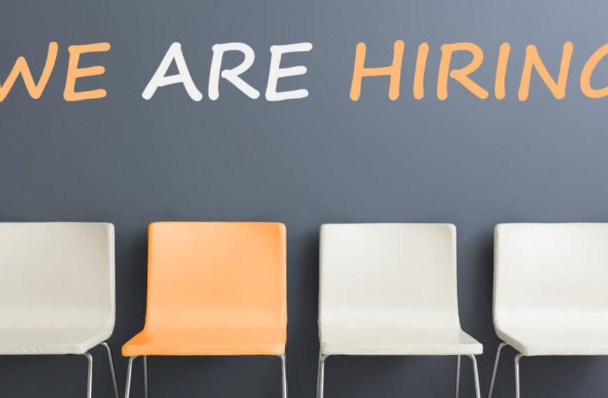 Four chairs are positioned in a row against a gray wall. The first, third, and fourth chairs are white, while the second chair is orange. Above them, the wall displays "WE ARE HIRING" in large white and orange letters—a familiar sight for those navigating job searches and employment agencies in Metro Manila.