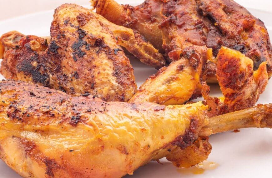 The best-grilled, seasoned chicken pieces with a golden-brown crust are served on a white plate. Perfectly charred for that flame-grilled texture, they're infused with visible spices and boast a juicy appearance. This appetizing dish would be right at home in Pangasinan's top restaurants.