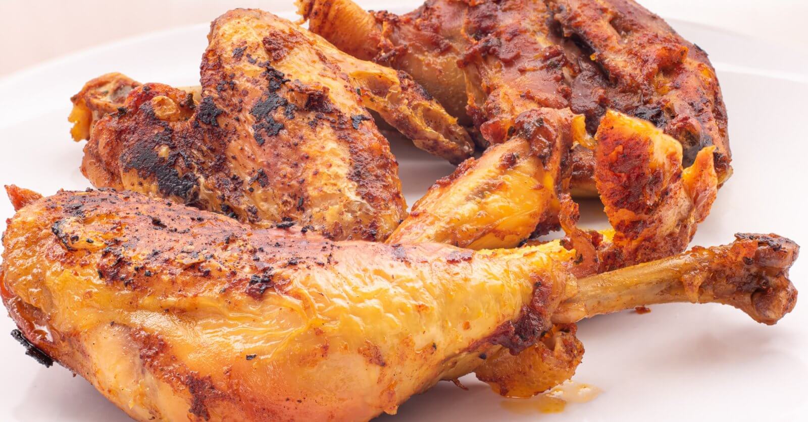 The best-grilled, seasoned chicken pieces with a golden-brown crust are served on a white plate. Perfectly charred for that flame-grilled texture, they're infused with visible spices and boast a juicy appearance. This appetizing dish would be right at home in Pangasinan's top restaurants.