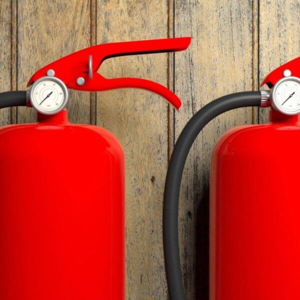 Two bright red fire extinguishers with black hoses and pressure gauges are mounted against a rustic wooden wall in Manila. The sleek, vibrant red of the extinguishers contrasts with the natural wood texture, while suppliers ensure timely fire extinguisher refills to maintain safety standards.