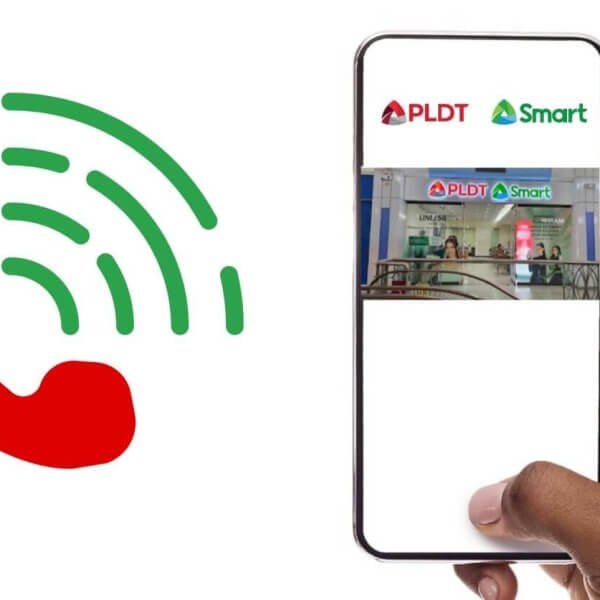 A hand holds a smartphone displaying an Experience Hub Center in Metro Manila, showcasing the PLDT SMART store interior with branding. To the left, a large red phone icon with green signal waves depicts communication. The white background emphasizes the phone and logo elements.
