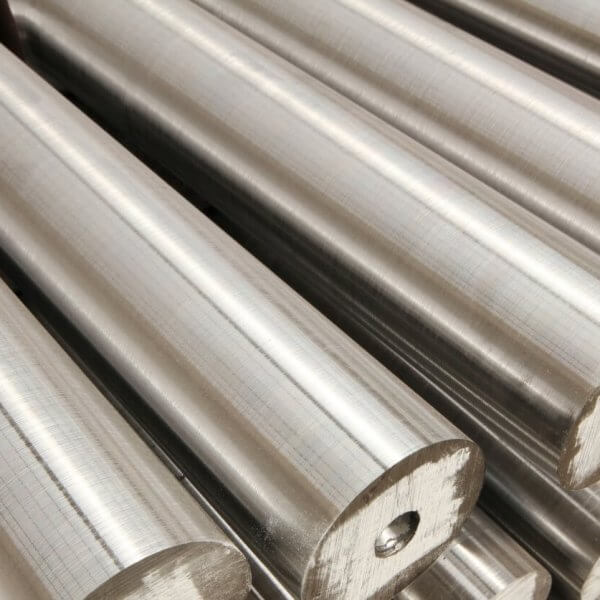 Close-up of several smooth, cylindrical metal rods stacked in parallel rows. Sourced from the best steel suppliers, these rods have a shiny, reflective surface and consistent diameter. Each rod has a small central hole at one end, adding a pattern to the otherwise uniform texture.