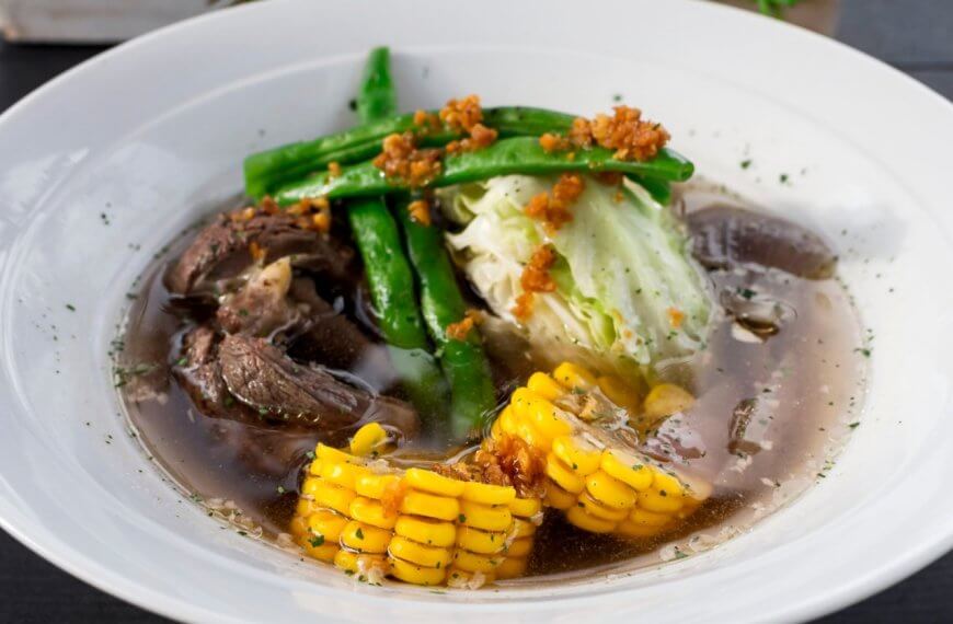 A bowl of the best soup in Batangas City, featuring tender beef, sweet corn, crisp cabbage, and fresh green beans in a clear broth, offers a delightful taste that local restaurants proudly serve.