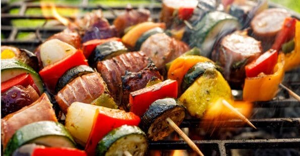 Grilled skewers with zucchini, bell peppers, onions, and meat sizzle over open flames, reminiscent of a vibrant evening in Iligan City.