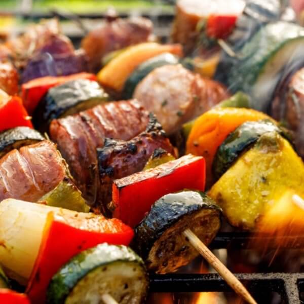 Grilled skewers with zucchini, bell peppers, onions, and meat sizzle over open flames, reminiscent of a vibrant evening in Iligan City.