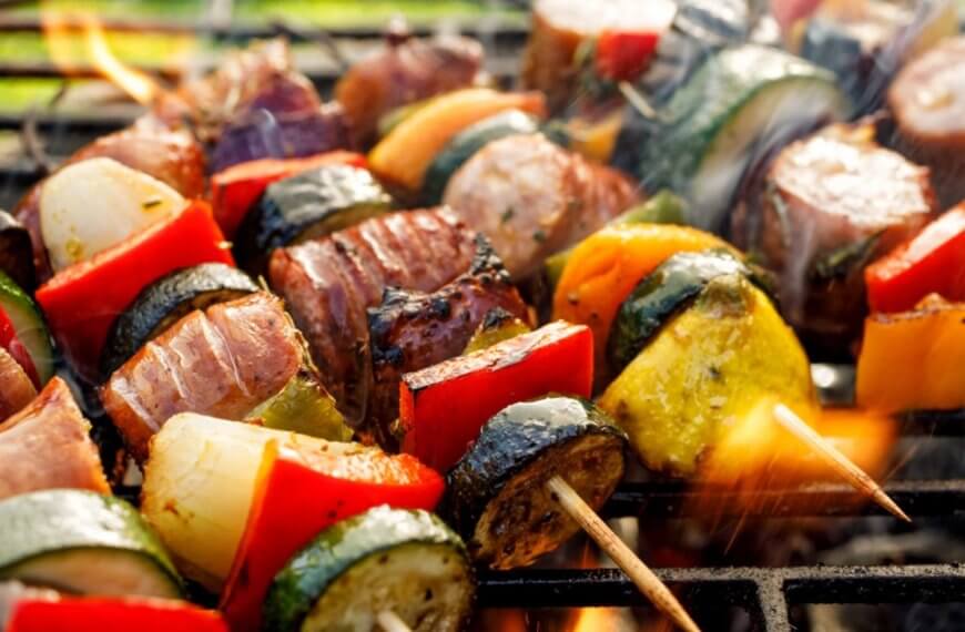 Grilled skewers with zucchini, bell peppers, onions, and meat sizzle over open flames, reminiscent of a vibrant evening in Iligan City.