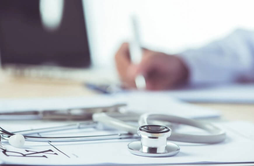 Close-up of a stethoscope and an infectious disease physician's hand writing on a clipboard, with a prescription pad in the background. This snapshot captures the dedication of one of Metro Manila's best medical professionals.