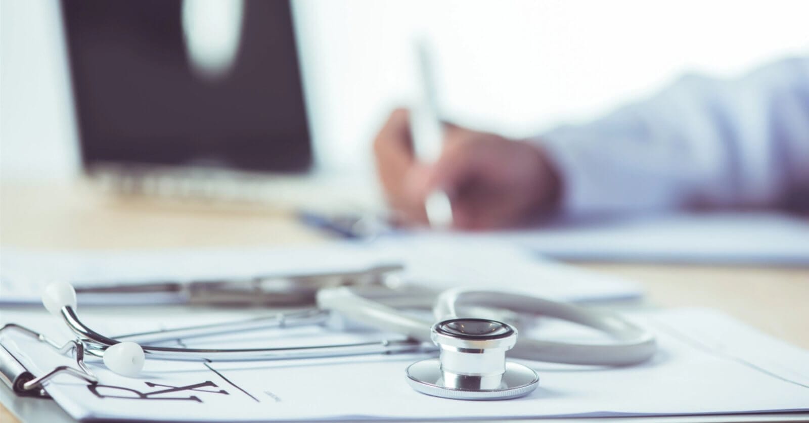 Close-up of a stethoscope and an infectious disease physician's hand writing on a clipboard, with a prescription pad in the background. This snapshot captures the dedication of one of Metro Manila's best medical professionals.