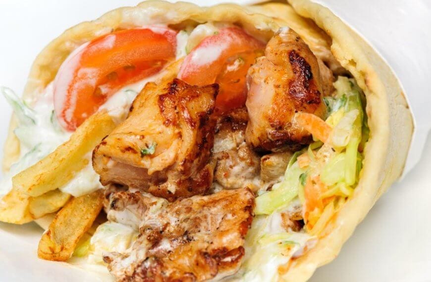 Close-up of a chicken wrap with grilled meat, lettuce, tomatoes, fries, and creamy sauce, wrapped in flatbread—one of the 23 Best dishes you'll find at top restaurants in Marawi City.