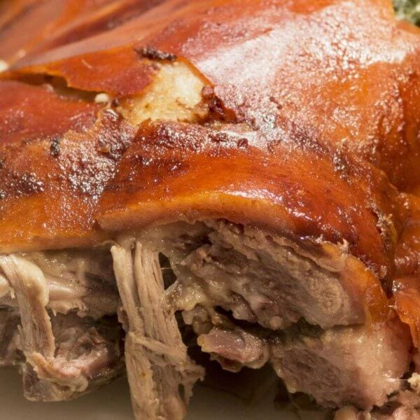 Close-up of crispy roast pork with golden skin and tender meat on a white plate, reminiscent of the flavors celebrated in Meycauayan's renowned restaurants.