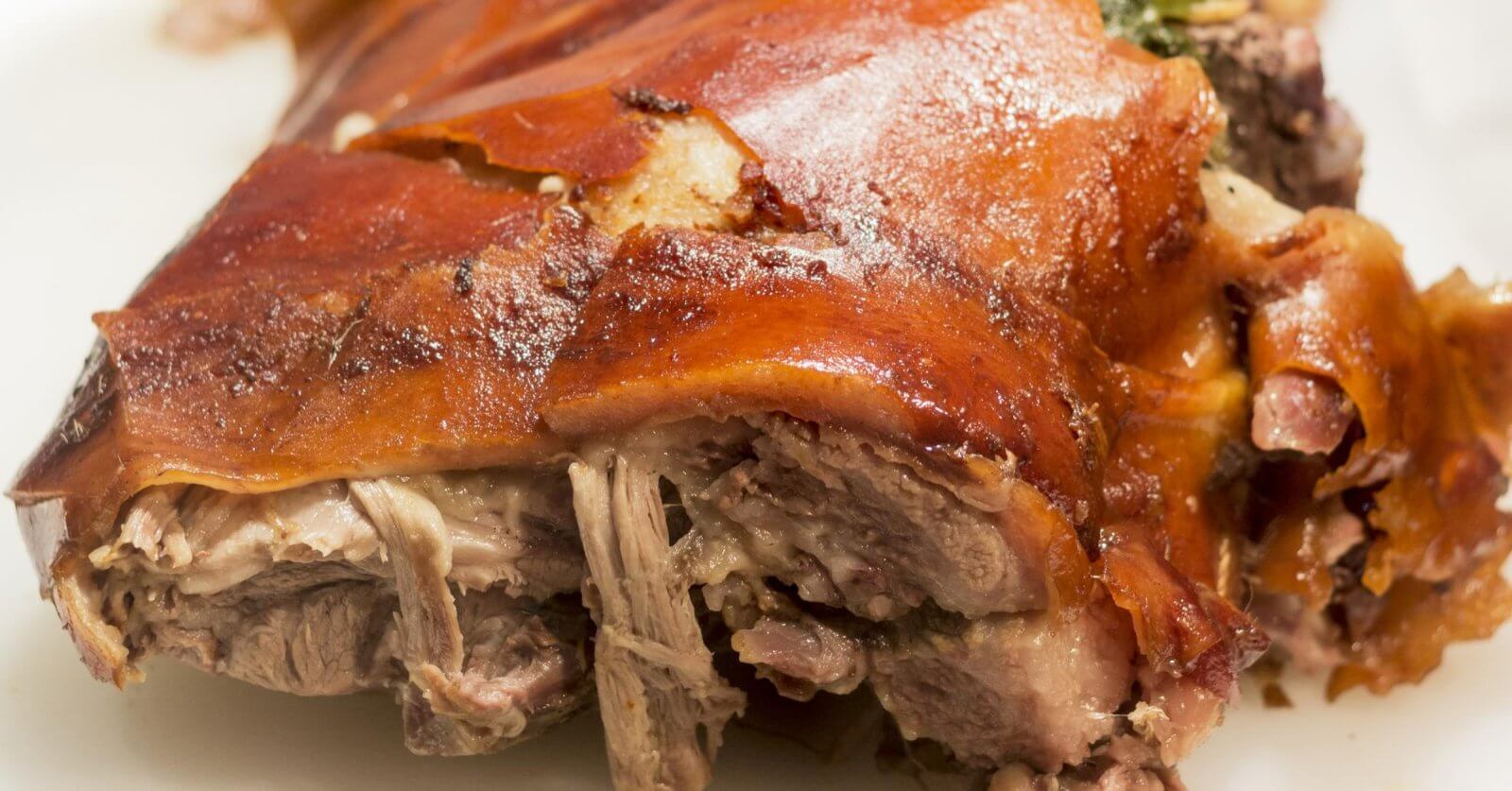 Close-up of crispy roast pork with golden skin and tender meat on a white plate, reminiscent of the flavors celebrated in Meycauayan's renowned restaurants.