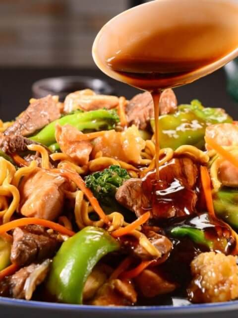 A plate of stir-fried noodles with beef, chicken, broccoli, and bell peppers being topped with soy sauce provides a mouth-watering experience. You can savor this delectable dish at one of the best restaurants in Robinsons Galleria.