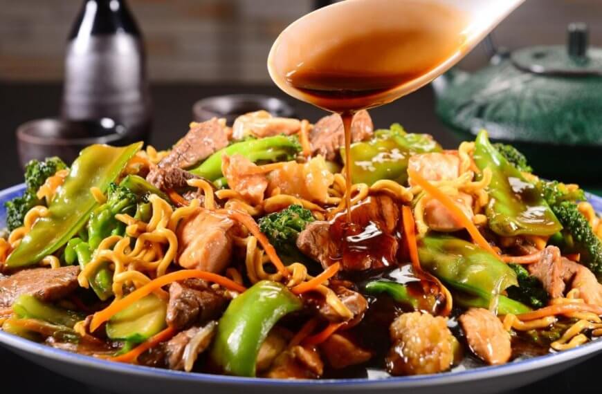 A plate of stir-fried noodles with beef, chicken, broccoli, and bell peppers being topped with soy sauce provides a mouth-watering experience. You can savor this delectable dish at one of the best restaurants in Robinsons Galleria.